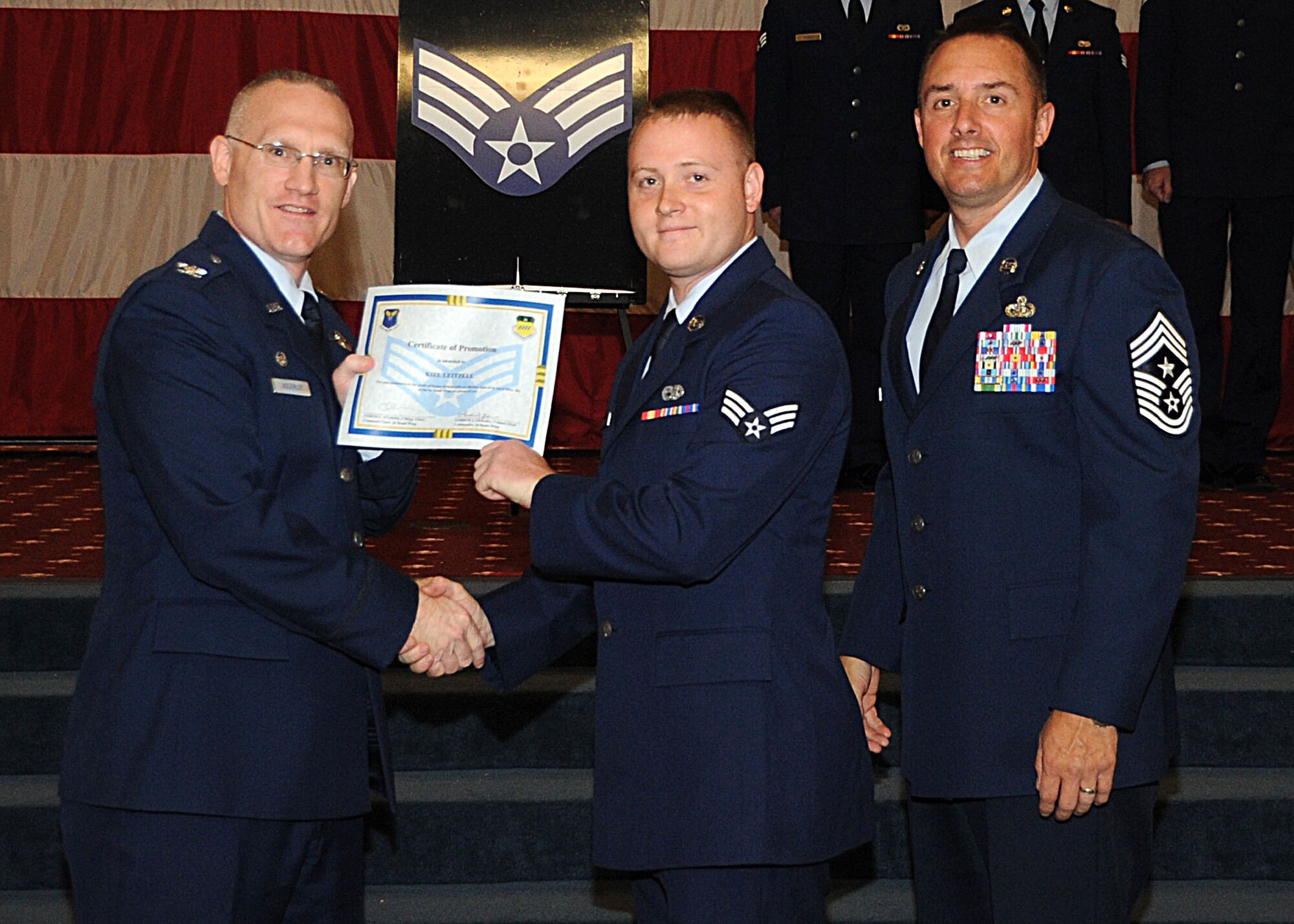 Senior Airman Kiel Leitzell, 2nd Maintenance Squadron, receives a certificate of promotion from Col. Michael Adderley, 2nd Operations Group commander, and Chief Master Sgt. Curtis Storms, 2nd Bomb Wing command chief, during the Wing Promotion Ceremony on Barksdale Air Force Base, La., April 30, 2014. (U.S. Air Force photo/Senior Airman Kristin High)