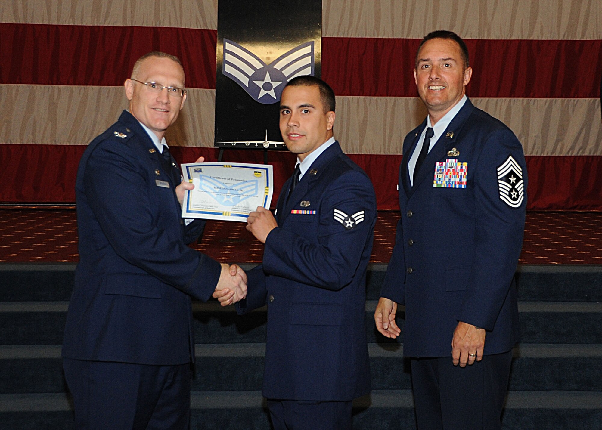 Senior Airman Rogelio Garcia, 2nd Maintenance Squadron, receives a certificate of promotion from Col. Michael Adderley, 2nd Operations Group commander, and Chief Master Sgt. Curtis Storms, 2nd Bomb Wing command chief, during the Wing Promotion Ceremony on Barksdale Air Force Base, La., April 30, 2014. (U.S. Air Force photo/Senior Airman Kristin High)