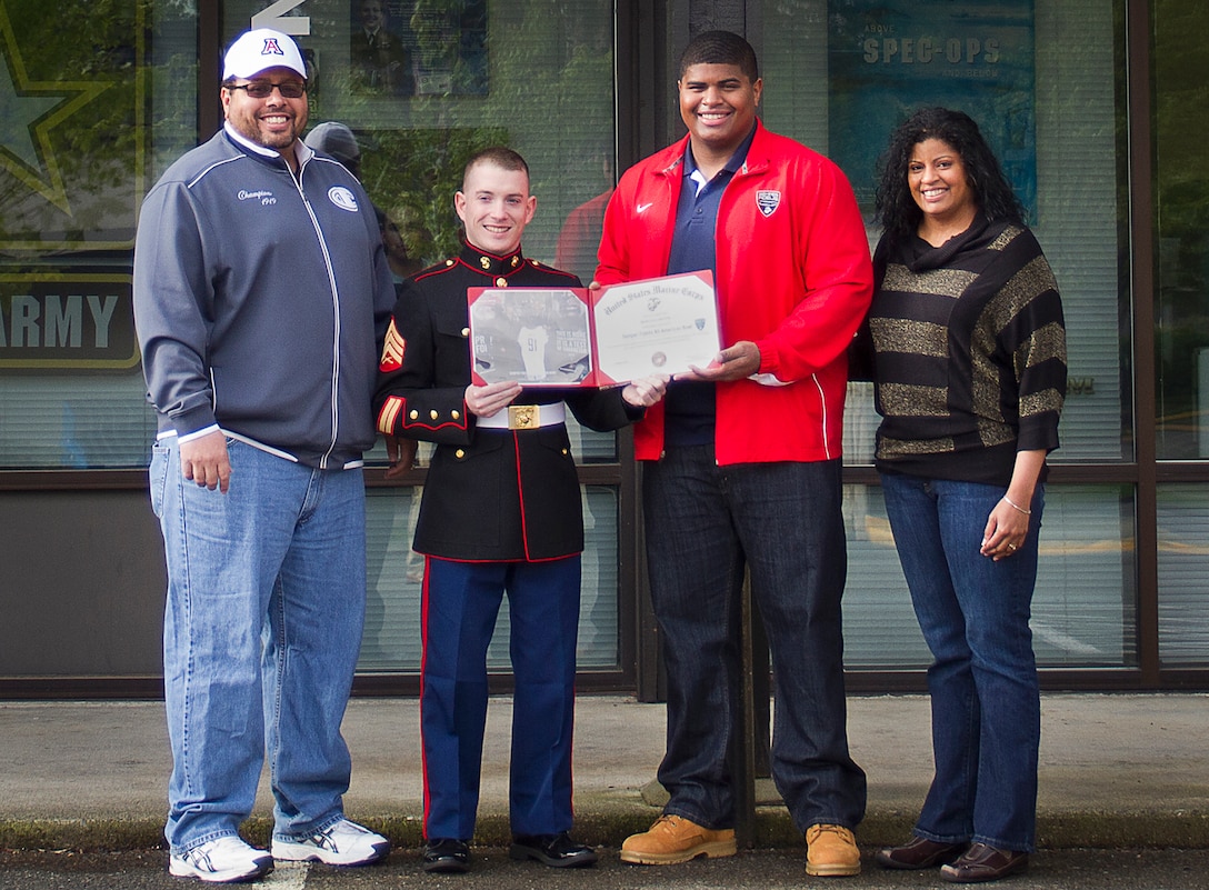 Marcus Griffin (third from left), a standout defensive lineman for the Bellevue High School Wolverines and 18-year-old native of Bellevue, Wash., stands alongside his parents and accepts a Semper Fidelis All-American Bowl certificate of commendation from Sgt. Christopher Noury (second from left), a career counselor with Marine Corps Recruiting Substation Bellevue, during a ceremony at Marine Corps Recruiting Substation Bellevue, Wash., May 9, 2014. Griffin was among 90 student athletes selected as Semper Fi All-Americans for their dedication to the community, classroom and on the gridiron. Griffin was the sole Washington State student selected to participate in the Semper Fidelis All-American Bowl at the StubHub Center in Carson, Calif., Jan. 5. In June, Griffin will begin attending the University of Arizona on a football scholarship.(U.S. Marine Corps photo by Sgt. Reece Lodder)