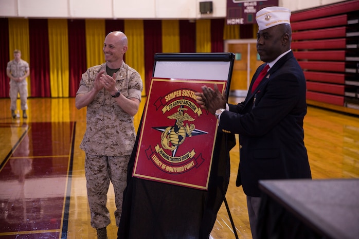 Lt. Col. Jesse Kemp (left), the commanding officer of 2nd Supply Battalion, 2nd Marine Logistics Group, and Dr. James Averhart Jr., the national president of the Montford Point Marine Association stand before the unit's new logo during a ceremony aboard Camp Lejeune, N.C., May 6, 2014. The new logo links the battalion with the heritage of the African-American Marines who trained at Montford Point, N.C., and carried out logistical missions in the Pacific during World War II