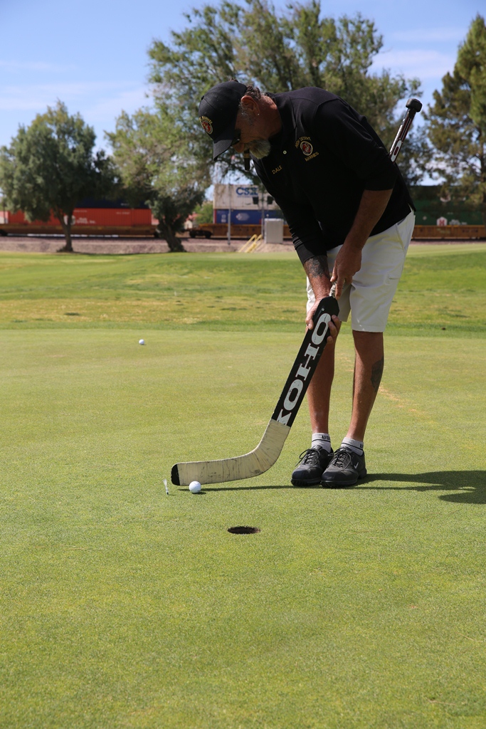 A member of the High Desert Marines puts using a hockey stick on the ‘utility hole’, during a Navy-Marine Corps fund drive golf tournament, April 27, at Tees and Trees Golf Course outside of Marine Corps Logistics Base Barstow, Calif. All proceeds went to
support the Navy-Marine Corps Relief Society.