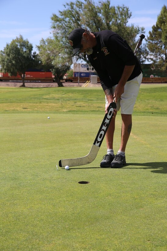 A member of the High Desert Marines puts using a hockey stick on the ‘utility hole’, during a Navy-Marine Corps fund drive golf tournament, April 27, at Tees and Trees Golf Course outside of Marine Corps Logistics Base Barstow, Calif. All proceeds went to
support the Navy-Marine Corps Relief Society.