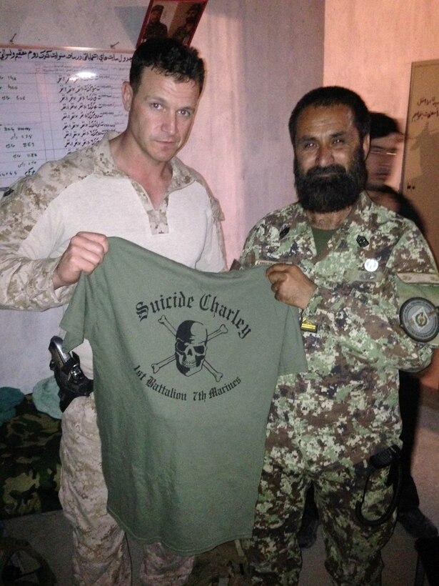 First Sgt. Jordan Freeland, company first sergeant, “Suicide” Charley Company, 1st Battalion, 7th Marine Regiment, and a native of Butte, California, presents a company shirt to an Afghan National Army soldier at Forward Operating Base Sabit Qadam, Afghanistan, May 4, 2014. The company turned over full security responsibilities of the FOB to the ANA, May 5. The infantrymen of 1st Bn., 7th Marines, were the final Marines to occupy FOB Sabit Qadam and the surrounding area in Sangin District.