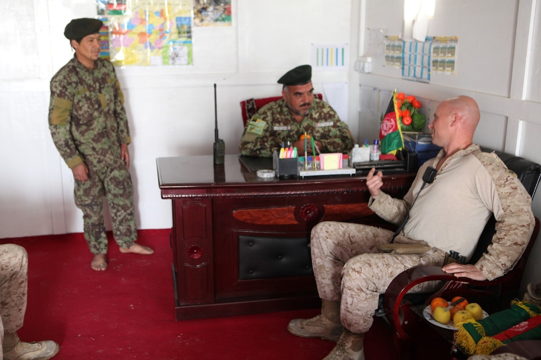 Captain John B. Naughton, right, the General Support Unit advisor with Security Force Assistance Advisor Team 2-215, speaks to Colonel Gul M. Pirdadkhil, center, GSU commander, 2nd Brigade, 215th Corps, Afghan National Army, aboard Forward Operating Base Nolay, Helmand province, Afghanistan, March 23, 2014. Following four years of Marines fighting in the Sangin District and advising their Afghan counterparts, Marines left Sangin for the final time, May 4, 2014.