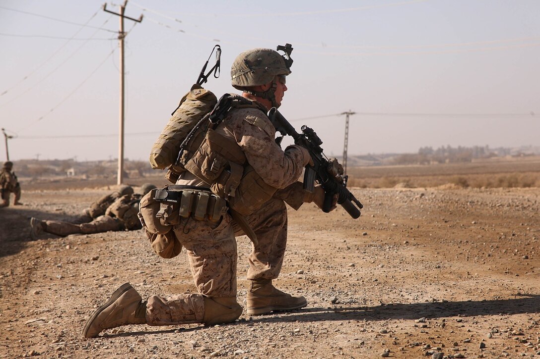 Corporal Brendan O'Bryant, a team leader with 1st Platoon, Company K, 3rd Battalion, 5th Marine Regiment, kneels during a security patrol here, Dec. 22. The Marines frequently patrol from the company's position to a recently established patrol base to keep the road clear of improvised explosive devices and monitor changes in the area.