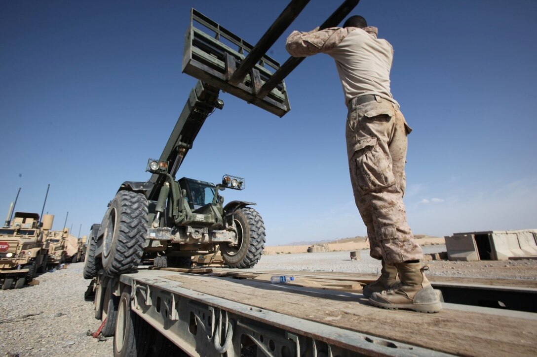 A Marine with Combat Logistics Battalion 7 signals down while loading a Tractor, Rubber-Tired, Articulated Steering, Multi-Purpose vehicle during the final retrograde operation aboard Forward Operating Base Nolay, Afghanistan, May 4, 2014. Following four years of Marines fighting in the Sangin District and advising their Afghan counterparts, Marines left Sangin for the final time, May 4, 2014.