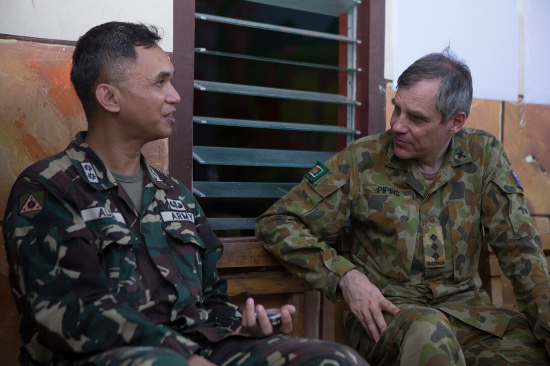Philippine Army Lt. Col. Erwin A. Alea, left, assistant chief of staff of civil military operations, with 8th Infantry Division, Camp Lukban, Catbalogan City and Australian Army Father Bryan Pipins, right, SJ, chaplain, with 1st Armoured Regiment, stationed at Robertson Barracks, Darwin, Australia, converse during a cooperative health engagement during Balikatan 2014 at Fishermans Village Elementary School, Tacloban, Republic of the Philippines, May 10, 2014. The Armed Forces Philippines and U.S. have had a long-standing relationship and welcome the Australian Defence Forces increasing participation in Balikatan.