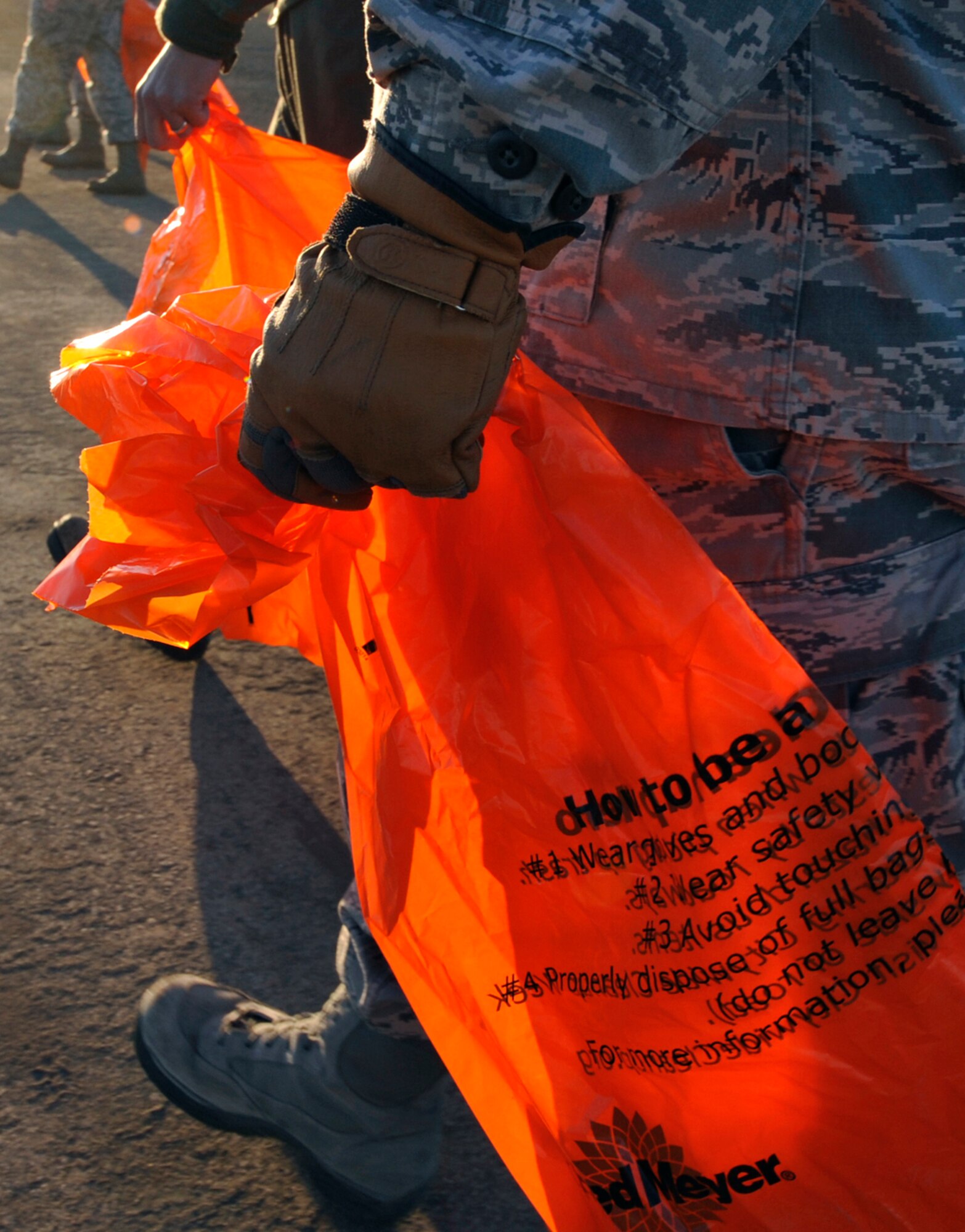 An Airman uses a bag to collect trash and debris during a foreign object damage walk on the flight line on Joint Base Elmendorf-Richardson, Alaska, May 9, 2014. The FOD walk provides a way to remove potentially hazardous objects and debris that come to rest on the flight line area as a result of the changing seasons and wind conditions. (U.S. Air Force photo/Airman 1st Class Tammie Ramsouer)