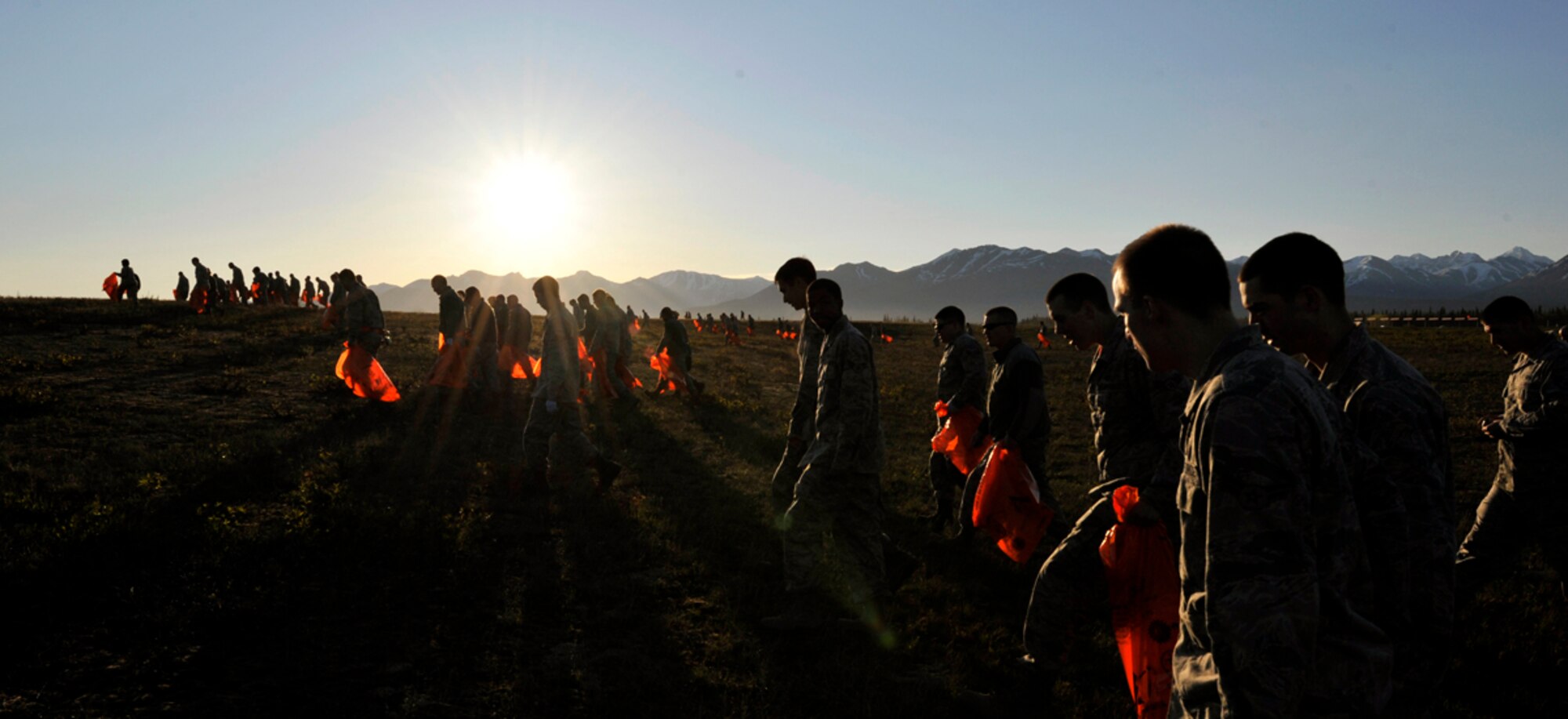 Airmen walk in a line as they pick up trash and debris during a foreign object damage walk on the flight line of Joint Base Elmendorf-Richardson, Alaska, May 9, 2014. During a FOD Walk, Airmen spread out and walk along the air ramp, picking up any loose objects they see, such as small rocks, which can be transported onto the ramp in the tire treads of vehicles. (U.S. Air Force photo/Airman 1st Class Tammie Ramsouer)