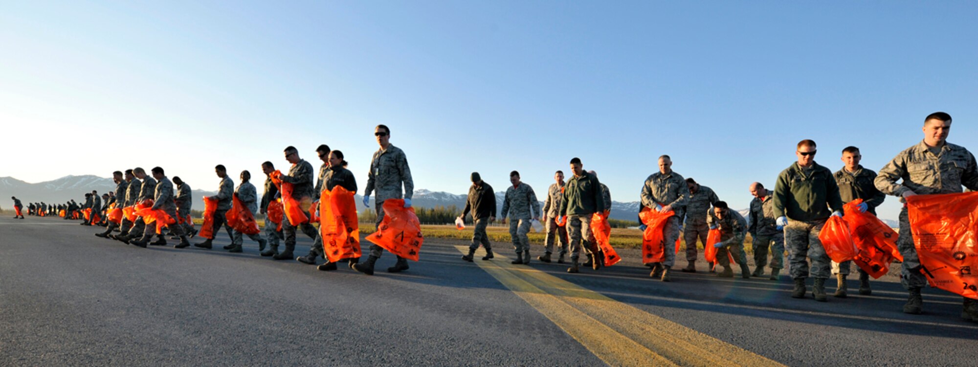 Airmen pick up trash and debris during the annual foreign object damage walk on the flight line of Joint Base Elmendorf-Richardson, Alaska, May 9, 2014. The FOD walk is done annually for the safety of the aircraft, Airmen and equipment used on the airfield. The runways are closed during the cleanup for the safety of the volunteers during the two-hour FOD walk. (U.S. Air Force photo/Airman 1st Class Tammie Ramsouer)