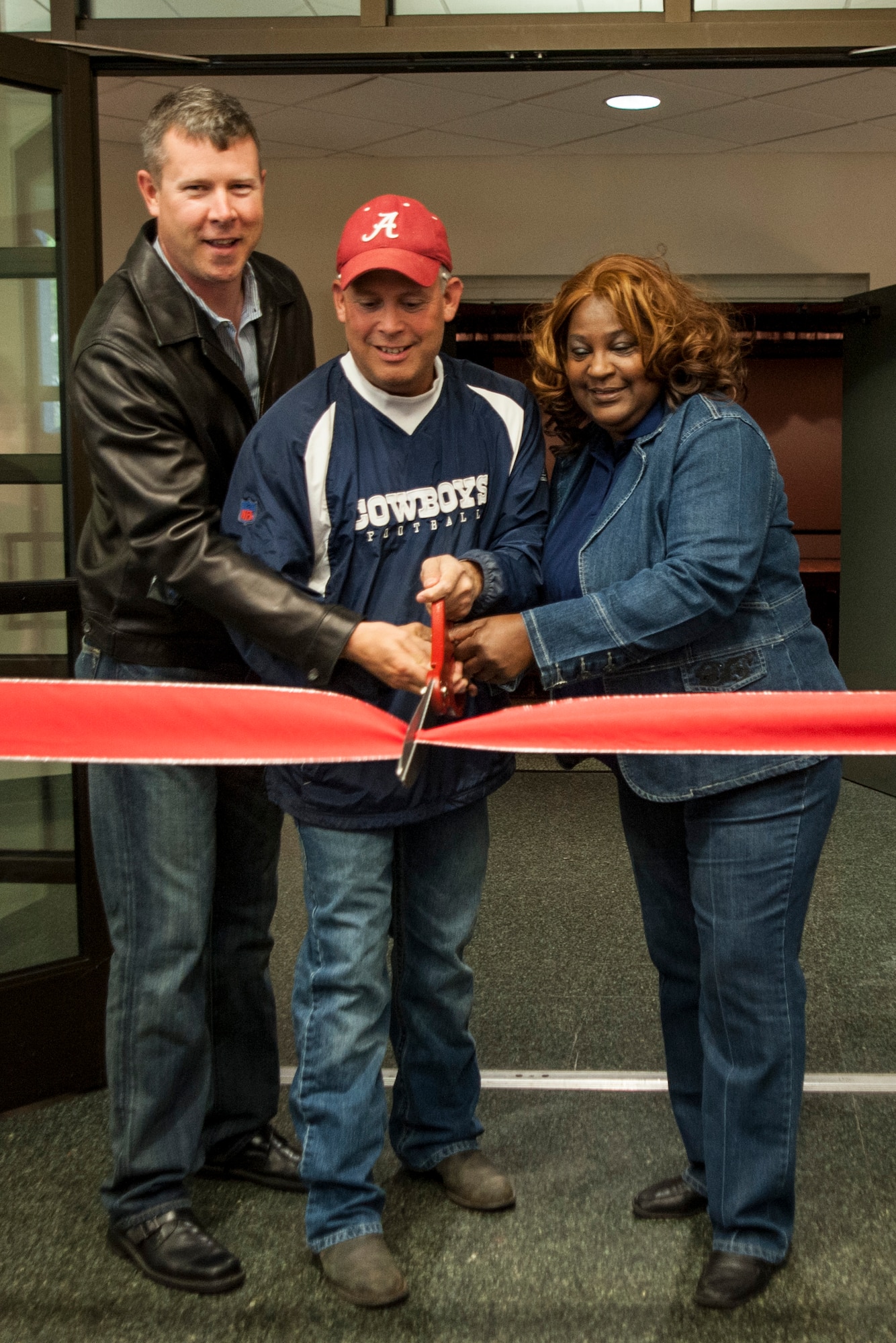 Lt. Col. Gregory Marty, 30th Force Support Squadron commander, Col. Jed Davis, 30th Mission Support Group commander, and Christine Stallwood, Vandenberg Army and Air Force Exchange Service general manager, cut a ceremonial ribbon marking the official re-opening of the base theater May 10, 2014, Vandenberg Air Force Base, Calif. (U.S. Air Force photo by Airman 1st Class Yvonne Morales/Released)