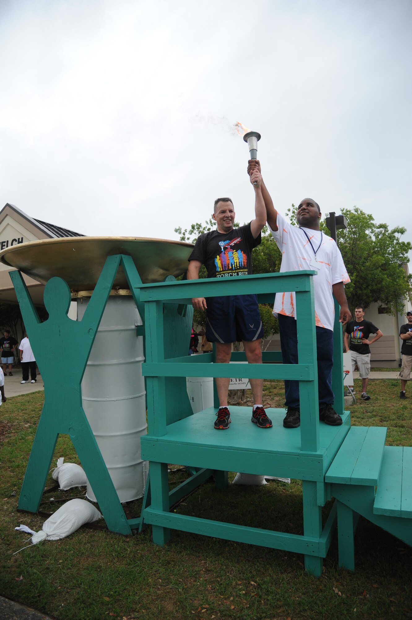 Brig. Gen. Patrick Higby, 81st Training Wing commander, and Rasaan Grear, athlete, hold the torch high after lighting the cauldron following the Mississippi's Special Olympics Law Enforcement Torch Run May 9, 2014. The torch was carried through 21 communities by more than 100 state law enforcement agencies. This is the 28th year Keesler has hosted the state Special Olympics. (U.S. Air Force photo by Kemberly Groue)