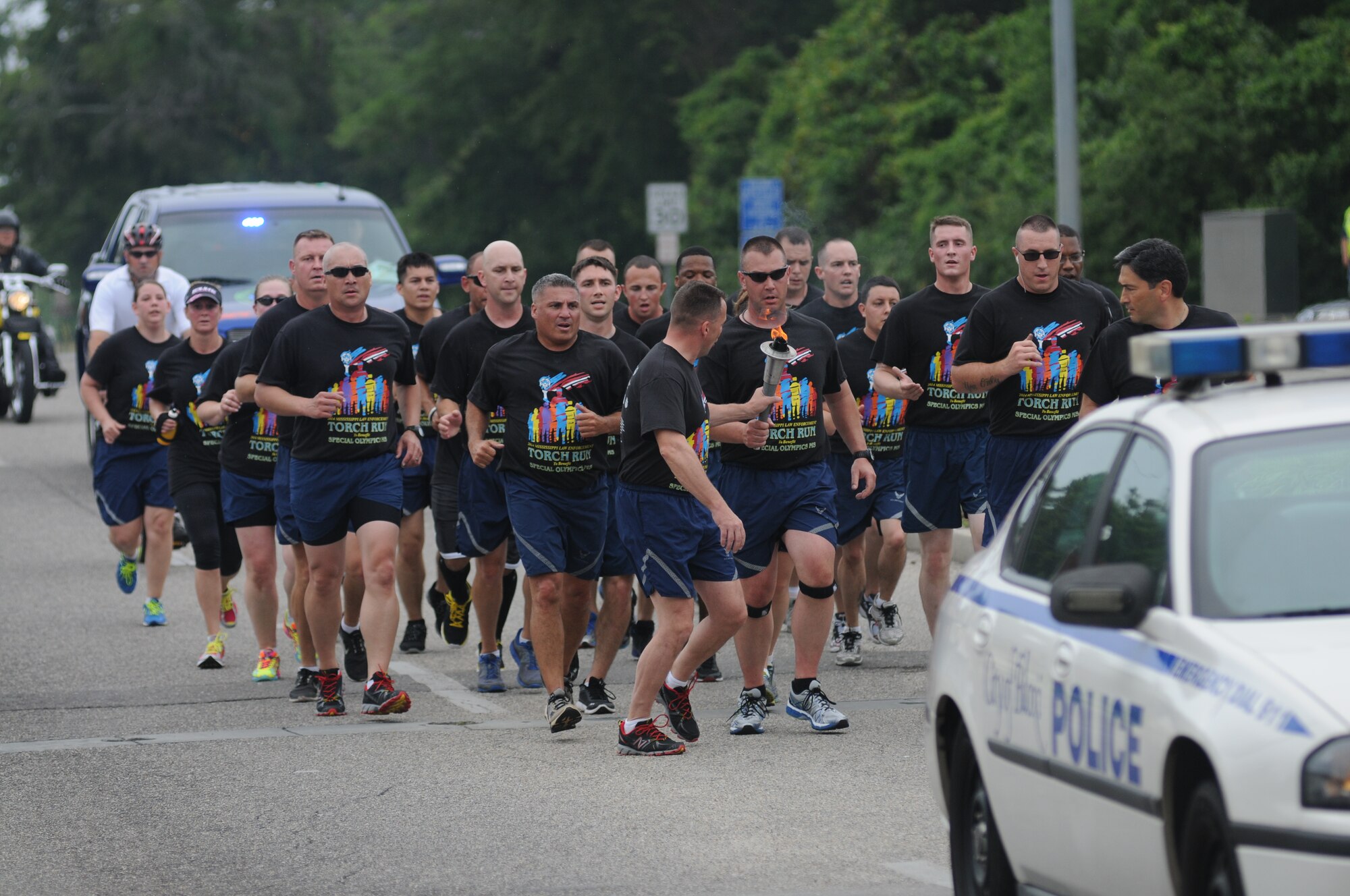 Brig. Gen. Patrick Higby, 81st Training Wing commander, receives the torch from Maj. Brian Fitzpatrick, 81st Security Forces Squadron commander, as they make their way into Keesler Air Force Base, Miss., alongside Col. René Romero, 81st TRW vice commander, and members of the 81st SFS for the final link in Mississippi's Special Olympics Law Enforcement Torch Run May 9, 2014.The torch was carried through 21 communities by more than 100 state law enforcement agencies. This is the 28th year Keesler has hosted the state Special Olympics. (U.S. Air Force photo by Kemberly Groue)
