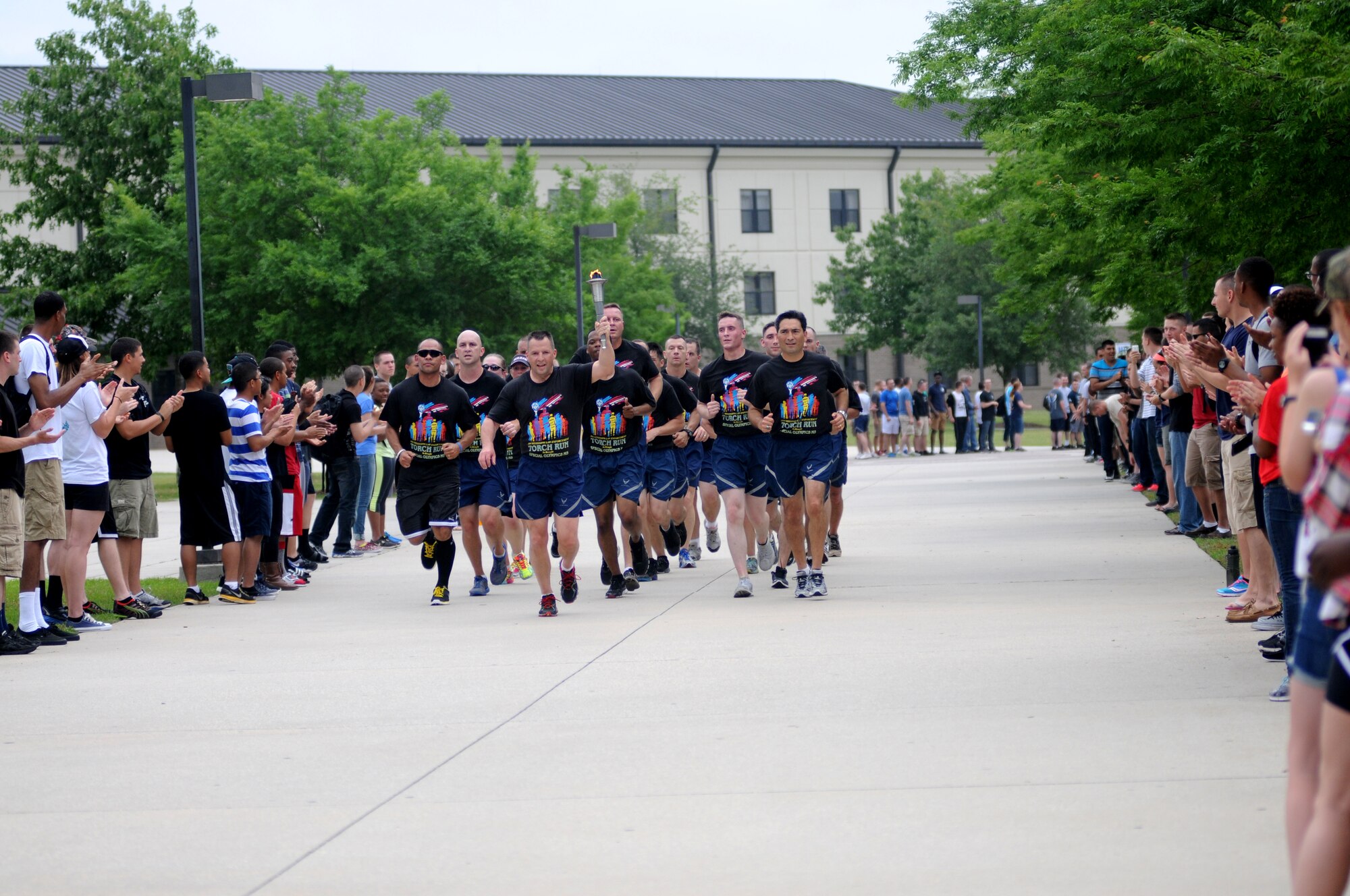 Brig. Gen. Patrick Higby, 81st Training Wing commander, Col. René Romero, 81st TRW vice commander, and members of the 81st Security Forces Squadron, lead the torch through a parade of Airmen on their way to light the cauldron during the Mississippi's Special Olympics Law Enforcement Torch Run May 9, 2014. The torch was carried through 21 communities by more than 100 state law enforcement agencies. This is the 28th year Keesler has hosted the state Special Olympics. (U.S. Air Force photo by Kemberly Groue)
