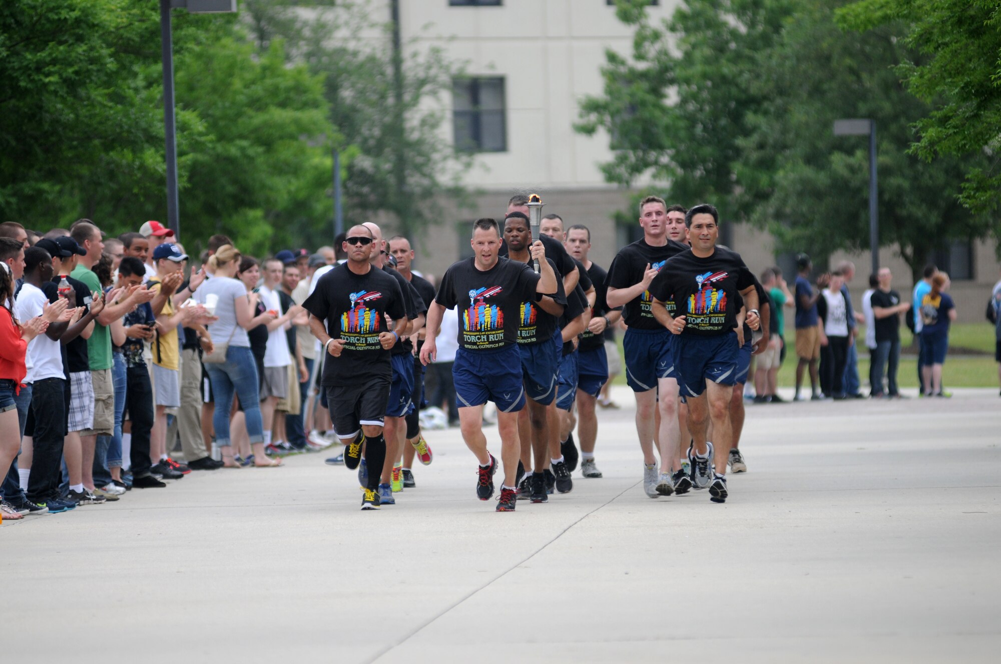 Brig. Gen. Patrick Higby, 81st Training Wing commander, Col. René Romero, 81st TRW vice commander, and members of the 81st Security Forces Squadron, lead the torch through a parade of Airmen on their way to light the cauldron during the Mississippi's Special Olympics Law Enforcement Torch Run May 9, 2014. The torch was carried through 21 communities by more than 100 state law enforcement agencies. This is the 28th year Keesler has hosted the state Special Olympics. (U.S. Air Force photo by Kemberly Groue)