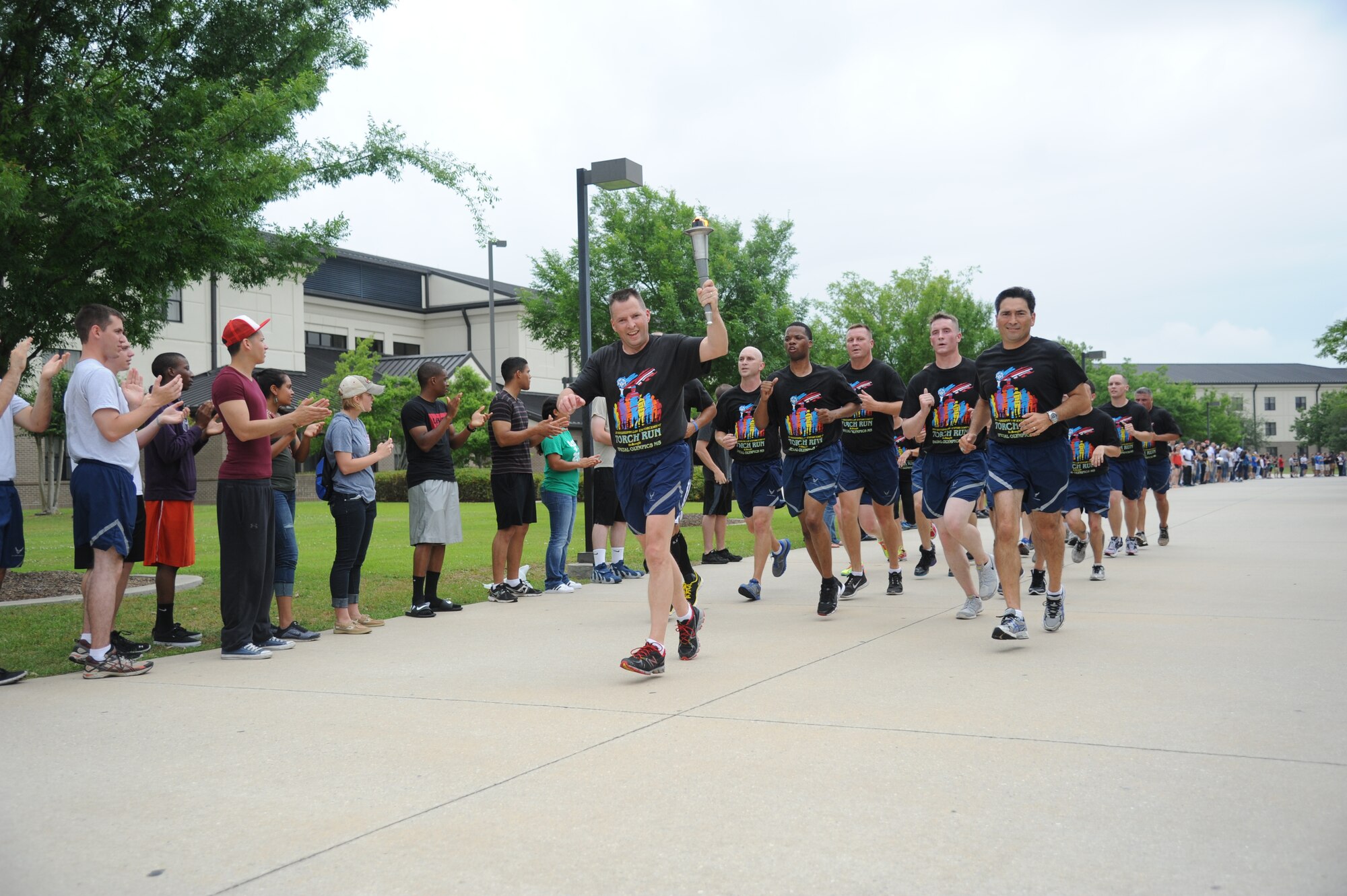 Brig. Gen. Patrick Higby, 81st Training Wing commander, Col. René Romero, 81st TRW vice commander, and members of the 81st Security Forces Squadron, lead the torch through a parade of Airmen on their way to light the cauldron during the Mississippi's Special Olympics Law Enforcement Torch Run May 9, 2014. The torch was carried through 21 communities by more than 100 state law enforcement agencies. This is the 28th year Keesler has hosted the state Special Olympics. (U.S. Air Force photo by Kemberly Groue)