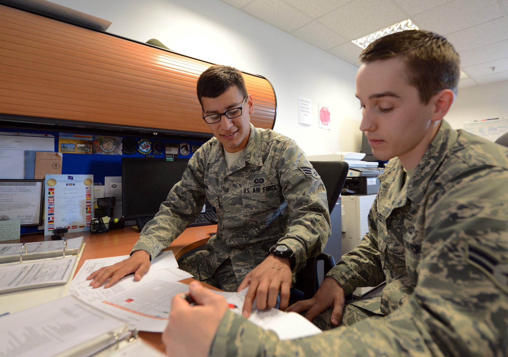 U.S. Air Force Senior Airman Jesus Lua, left, 67th Special Operations Squadron aviation resource management journeyman from Gettysburg, Pa., trains U.S. Air Force Airman 1st Class Nicholas Kiel, 67th SOS aviation resource management apprentice from Muskegon, Mich., on the flight authorization process May 12, 2014, on RAF Mildenhall, England. Lua earned the Square D Spotlight for exhibiting the Air Force Core Value of Excellence in All We Do. (U.S. Air Force photo by Airman 1st Class Kyla Gifford/Released)