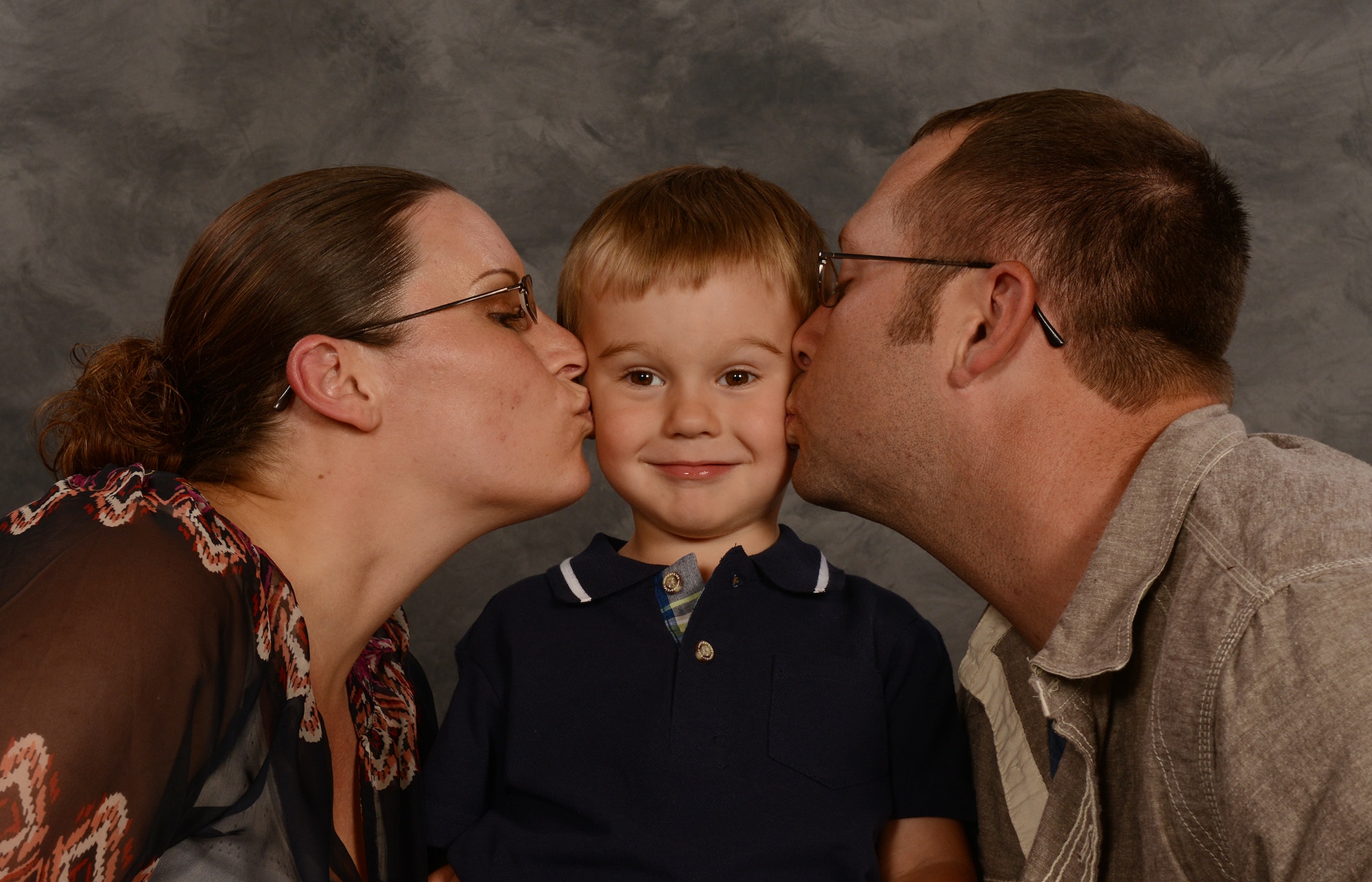 U.S. Air Force Staff Sgts. Amanda and Michael Griggs, 23d Component Maintenance Squadron aerospace propulsion craftsmen, kiss their son, Korbin, for a photo at Moody Air Force Base, Ga., May 8, 2014. Amanda Griggs has served seven years and is 24 weeks pregnant with her second child. (U.S. Air Force photo illustration by Senior Airman Tiffany M. Grigg/Released)