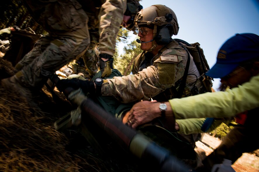Airmen from the 58th Rescue Squadron out of Nellis Air Force Base, Nev., and a Coconino County Sheriff’s Search and Rescue Unit volunteer place a victim onto a litter during an Angel Thunder mass-casualty exercise May 9, 2014, at Camp Navajo, Ariz. During the exercise, the response teams provided medical attention to more than 30 Air Force ROTC cadets who acted as victims. (U.S. Air Force photo by Staff Sgt. Jamal D. Sutter/Released) 
