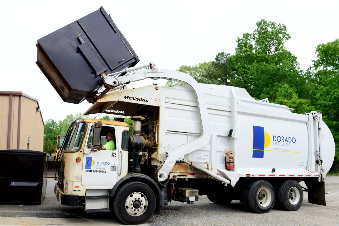 A front-loading garbage truck extracts waste from a dumpster at Fort Eustis, Va., May 7, 2014. More than 100 dumpsters are emptied daily. U.S. Air Force photo by Airman 1st Class Kimberly Nagle/Released)(Photo was cropped, levels were used and sharpened.)