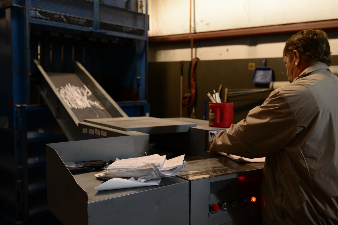 Thomas Gunter, 733rd Civil Engineering Division contracting officer representative, shreds paper at the Solid Waste and Recycle Center at Fort Eustis, Va., May 7, 2014. The SWRC has both a paper shredder and designator for classified and secret documents. Gunter hails from Berwick, Pa. (U.S. Air Force photo by Airman 1st Class Kimberly Nagle/Released)(Photo was cropped, color corrected and sharpened.)