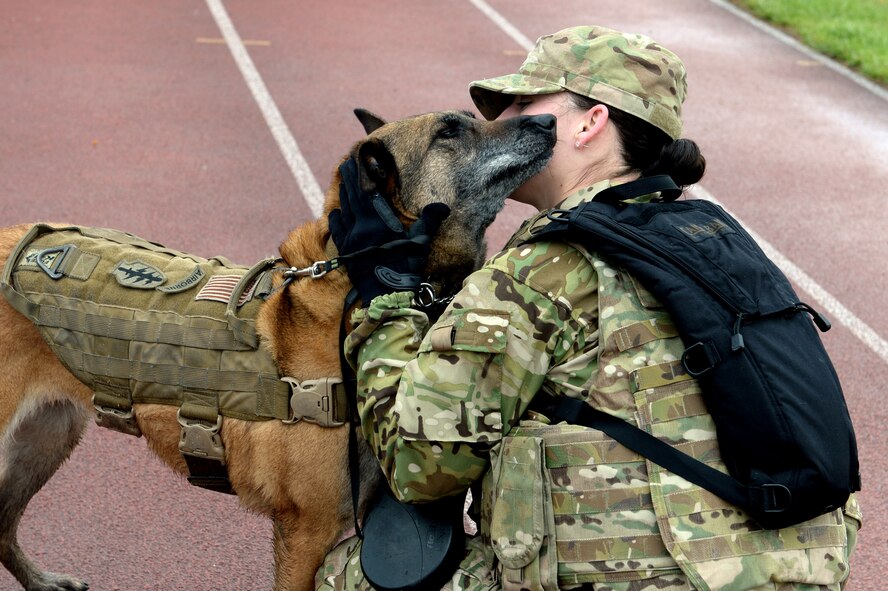 Military Working Dog Katya kisses the cheek of U.S. Air Force Staff Sgt. Shannon Hennessy, 52nd Security Forces Squadron MWD handler from Colusa, Calif., at Spangdahlem Air Base, Germany, May 12, 2014, after the Security Forces Memorial Ruck March. The march was held to honor those who made the ultimate sacrifice in the line of duty and recognize the service of base defenders. (U.S. Air Force photo by Senior Airman Alexis Siekert)