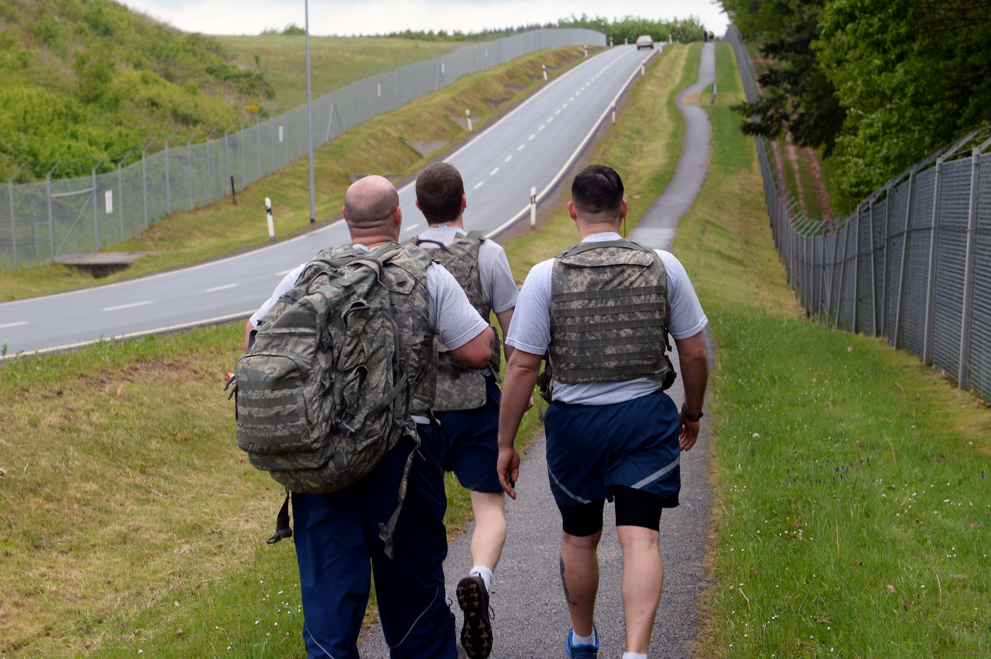 Three 52nd Security Forces Squadron patrolmen walk the perimeter of the base in the 10-kilometer Security Forces Memorial Ruck March at Spangdahlem Air Base, Germany, May 12, 2014. Participants were encouraged throughout the march to reflect on the loss of fallen security forces members. (U.S. Air Force photo by Senior Airman Alexis Siekert)