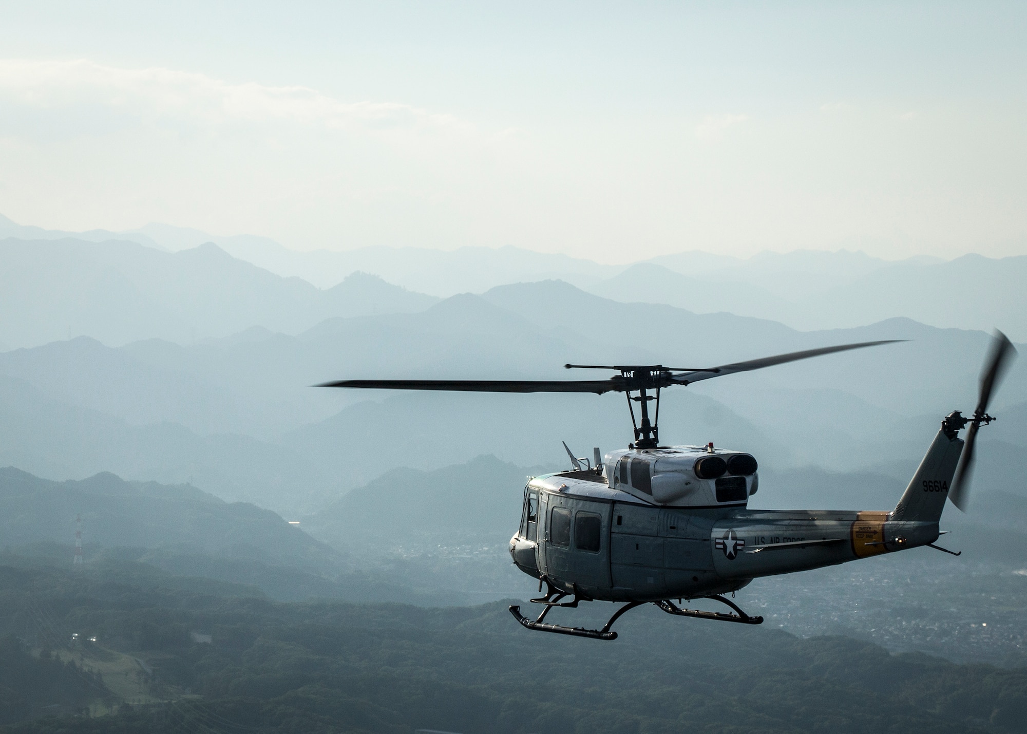 A UH-1N Huey with the 459th Airlift Squadron flies over the city of Fussa, in the Kanto Plains area, Japan, May 8, 2014.  Yokota Airmen regularly perform practice missions to be prepared to respond to any contingency.  (U.S Air Force photo by 2nd Lt. Ashley Wright/Released)