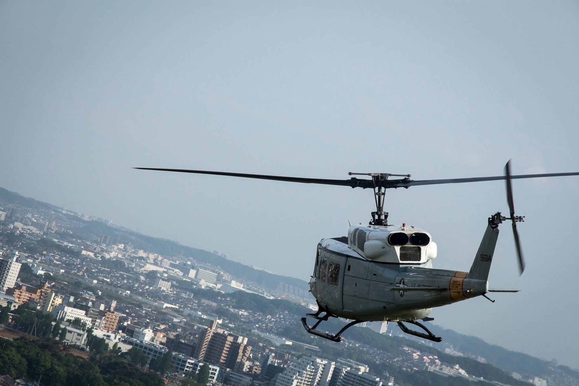 A UH-1N Huey from the 459th Airlift Squadron flies over the city of Fussa, in the Kanto Plains area, Japan, May 8, 2014.  Yokota Airmen regularly perform practice missions to be prepared to respond to any contingency.  (U.S Air Force photo by 2nd Lt. Ashley Wright/Released)