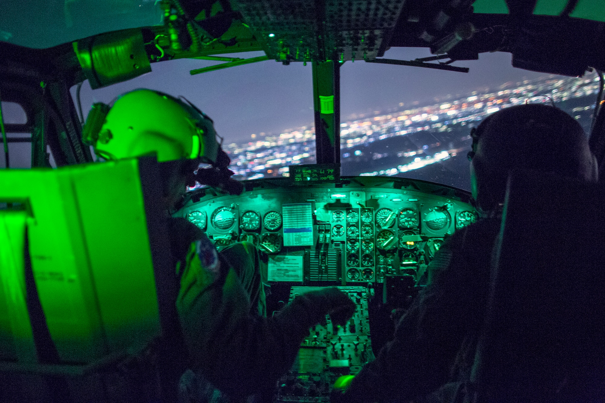 Left to right) 1st Lt. Jonathan Palka and Maj. TJ Martin, both UH-1N pilots from the 459th Airlift Squadron, fly above Yokota Air Base, Japan during night vision goggle training, May 7, 2014. Airmen from the 459 AS conduct night vision goggle training in order to maintain proficiency with their equipment. (U.S. Air Force photo by Osakabe Yasuo/Released)