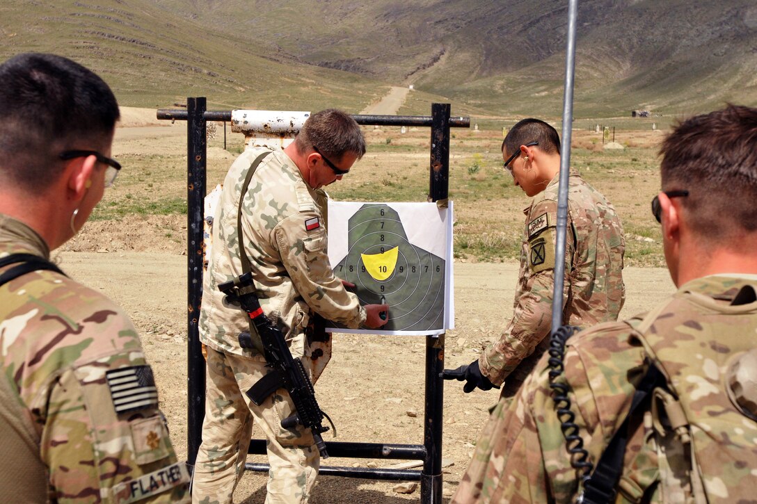 U.S. soldiers look on as Polish army Lt. Col. Piotr Sieminski, center left, counts the number of hits on a target after a qualification attempt by U.S. Army Pvt. Daniel Weaver, second from right, during the Polish army small-arms marksmanship range on Forward Operating Base Thunder, Afghanistan, May 1, 2014. Weaver and other soldiers are assigned to the 10th Mountain Division's 3rd Brigade Combat Team. The range was conducted to give the soldiers an opportunity to earn the Polish army's marksmanship badge.