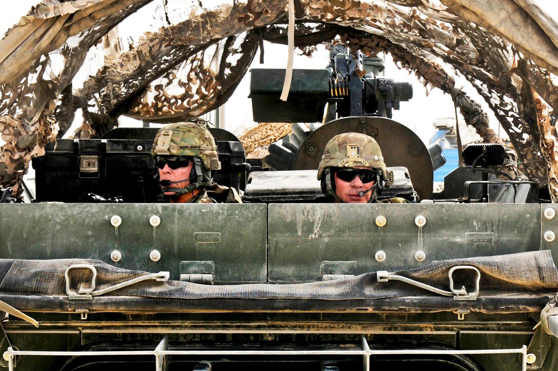 U.S. Army Lt. Col. Henry I. B. McNeilly, left, and U.S. Army Lt. Col. Thomas M. Feltey provide rear security in a Stryker armored vehicle as part of a convoy carrying the new commander of Regional Command Southin in Afghanistan's Kandahar province, July 11, 2013. McNeilly commands the 2nd Infantry Division's 1st Battalion, 6th Field Artillery Regiment and Feltey commands the 1st Infantry Division's 2nd Battalion, 23rd Infantry Regiment.  
