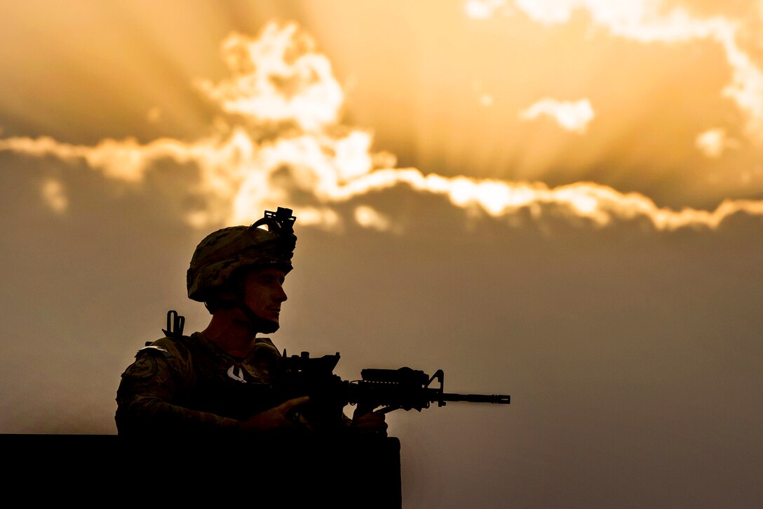 U.S. Air Force Airman 1st Class Alec Blackmon provides security from a rooftop as the sun sets on Camp Oqab in Kabul, Afghanistan, July 16, 2013. Blackmon is assigned to the 439th Air Expeditionary Advisory Squadron Security Forces. Camp Oqab is home to the 438th Air Expeditionary Wing, which is responsible for advising the growing Afghan air force.  
