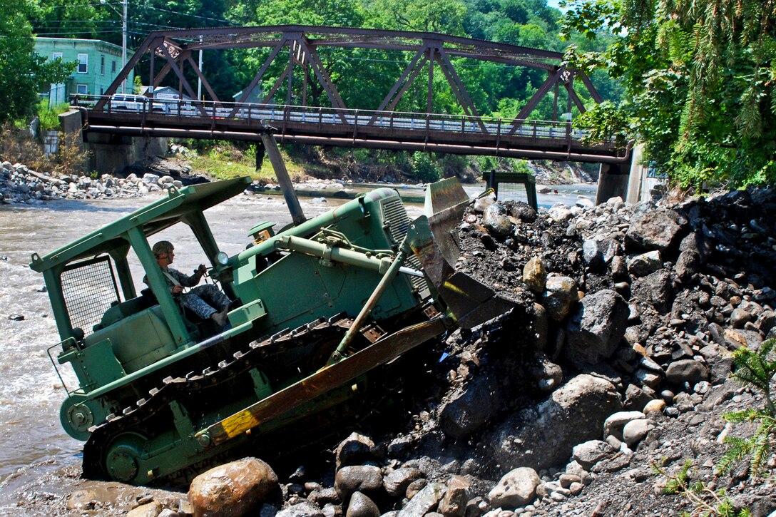 Army Pfc. Michael Bykowicz uses a bulldozer to remove rocks and other flood debris from Otsquago Creek in Fort Plain, N.Y., July 4, 2013. Bykowicz is assigned to the New York National Guard's 152nd Engineer Company. The debris had choked the creek's flow.  
