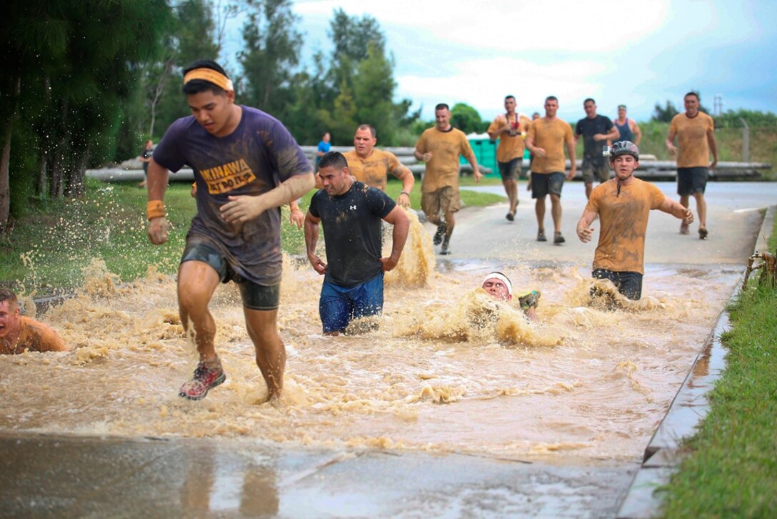 Participants race through a water pit May 10 during the Single Marine Program’s second annual Bushido Mud Run at Camp Hansen. More than 2,000 people gathered at Camp Hansen’s parade field to take part in the competition.