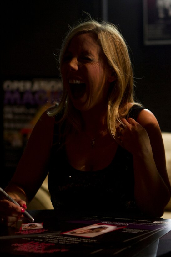 Mollie Gross, author and featured performer for a Military Spouse Appreciation Night at the Bob Hope Theater aboard Marine Corps Air Station Miramar, Calif., laughs as she draws mustaches on her photos and signs an autograph backstage before her performance, May 9. Gross authored the book “Confessions of a Marine Wife,” drawing her inspiration from the military lifestyle she inherited when she married an infantryman stationed at Marine Corps Base Camp Pendleton, Calif. The event, hosted by Marine Corps Community Services, featured pampering and entertainment provided by local companies to honor the sacrifice of the silent ranks of the air station and 3rd Marine Aircraft Wing: military spouses.