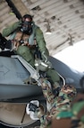Lt. Col. Henry Jeffress, 80th Fighter Squadron director of operations, passes his helmet to Senior Airman Brendan Walsh, 8th Aircraft Maintenance Squadron crew chief, during exercise Beverly Bulldog 14-2 at Kunsan Air Base, Republic of Korea, May 9, 2014. This exercise tested the Wolf Pack's ability to perform its mission while under threat of chemical attack. (U.S. Air Force photo by Staff Sgt. Clayton Lenhardt/Released)