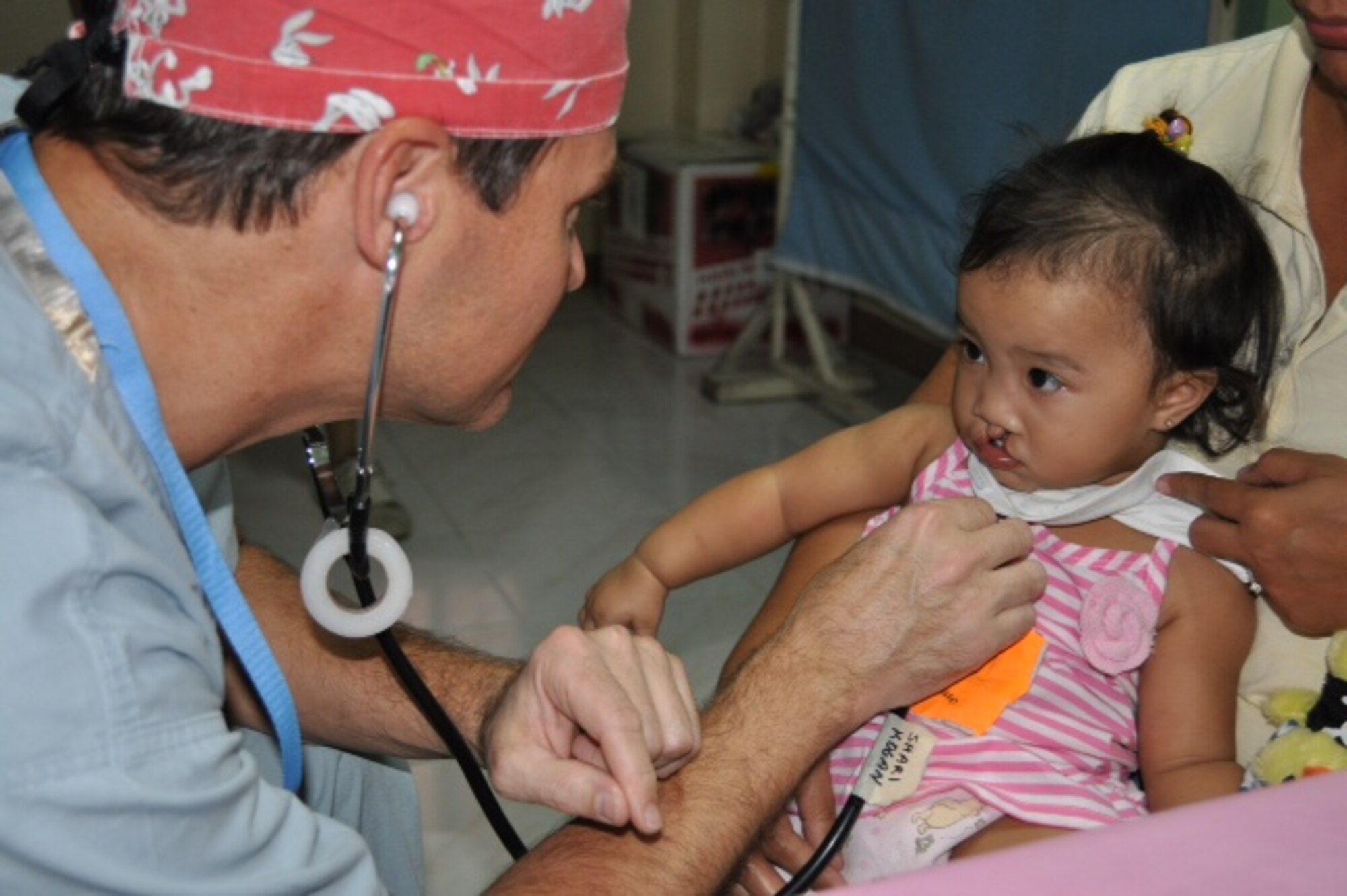 Lt. Col. Jeffrey Healy, left, a flight surgeon with the 624th Aeromedical Staging Squadron, Joint Base Pearl Harbor-Hickam, Hawaii, checks the heartbeat of a young patient, right, whom he has operated on to correct a cleft palate at a local hospital in Bacolod, Philippines, Feb. 27, 2014. Dr. Healy has traveled to the Philippines, India, China and Vietnam, volunteering his medical skills as a civilian doctor to the Aloha Medical Mission, a volunteer organization based in Honolulu that provides free health care to the underserved people in Hawaii and across the Pacific and beyond. (Courtesy photo/Dr. Jeffrey Healy)