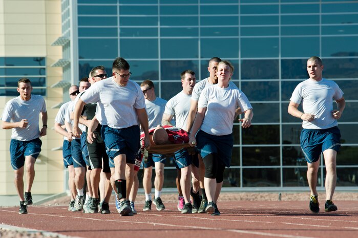 Participates carry a mannequin on a litter once around the Warrior Fitness Center track during the Warrior Trained Fitness training session May 13, 2014, at Nellis Air Force Base, Nev. The two participants at the end of the group had to sprint to the front and signal for the next two runners to come forward. (U.S. Air Force photo by Senior Airman Timothy Young)