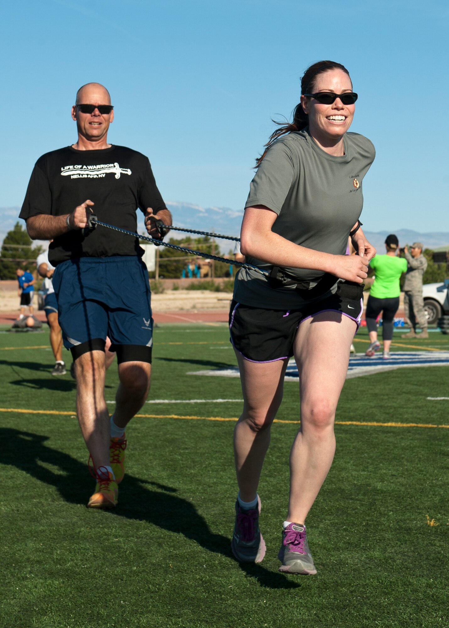 U.S. Air Force Capt. Jennifer Schicker (front), U.S. Air Force Warfare Center deputy of protocol, sprints during the resistance portion of the Warrior Trained Fitness training session while being assisted by Master Sgt. Luke McCarthy, 99th Security Forces Squadron NCO in charge of range infrastructure, at the Warrior Fitness Center May 13, 2014, at Nellis Air Force Base, Nev. WTF had several different exercise stations set up, each designed to strengthen the upper body, lower body, and core. (U.S. Air Force photo by Airman 1st Class Thomas Spangler)