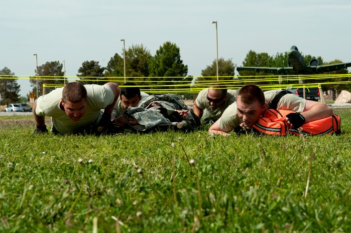 Airmen crawl under simulated barb wire during the 99th Medical Group’s Life of a Warrior Challenge May 9, 2014 at Nellis Air Force Base, Nev. Teams were responsible for transporting a bag of medical equipment and a mannequin on a litter through all eight portions of the event. (U.S. Air Force photo by Senior Airman Timothy Young)