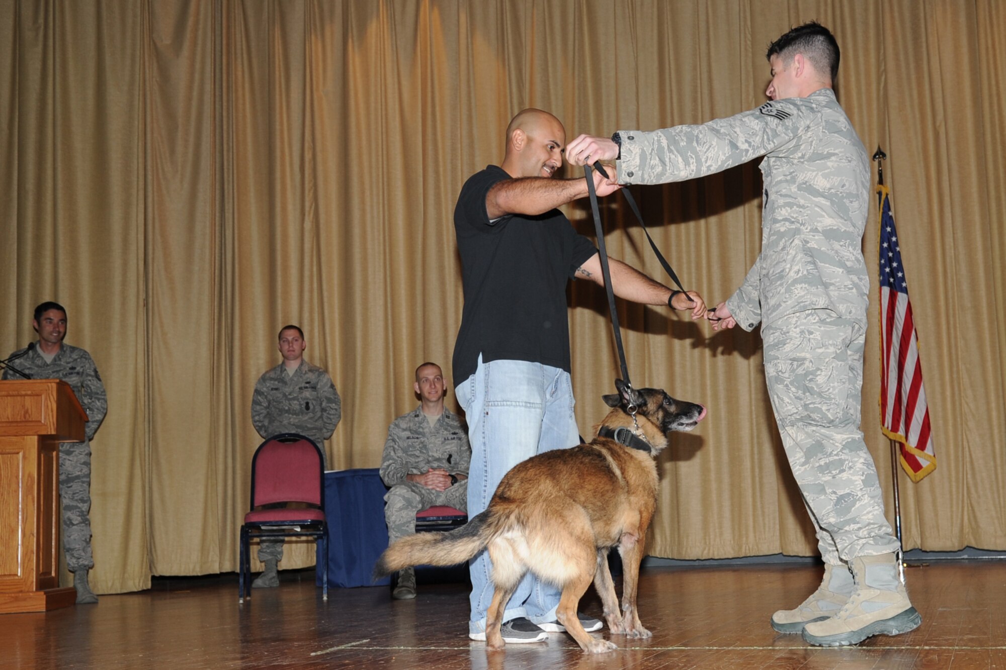 GOODFELLOW AIR FORCE BASE, Texas -- Staff Sgt. Donald Weaver, 17th Security Forces Squadron military working dog handler, hands Rocky’s, 17th SFS MWD, leash to Ronnie G. Garcia, Department of Homeland Security Explosive Detection K9 handler, during a retirement ceremony at the base theater here May 9. Garcia was Rocky’s handler from January 2008 to July 2010. (U.S. Air Force photo/ Staff Sgt. Laura R. McFarlane)