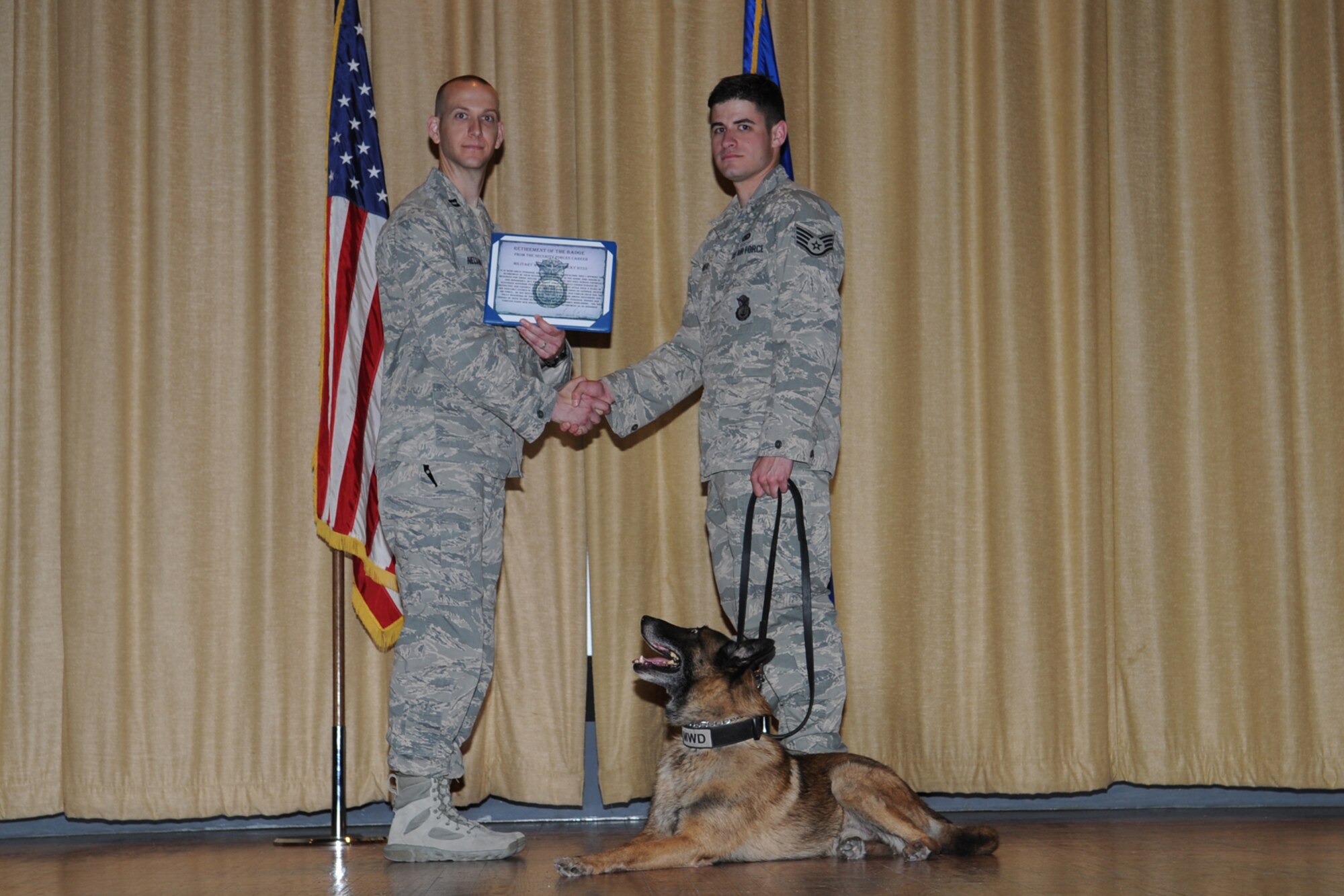 GOODFELLOW AIR FORCE BASE, Texas -- Capt. Nelson, 17th Security Forces Squadron Commander, presents Staff Sgt. Donald T. Weaver, 17th SFS military working dog handler and Rocky, 17th SFS MWD, with a retirement of the badge certificate during a retirement ceremony at the base theater here May 9. The ceremony recognized Rocky’s nine years of active duty commitment to the Air Force. (U.S. Air Force photo/ Staff Sgt. Laura R. McFarlane)