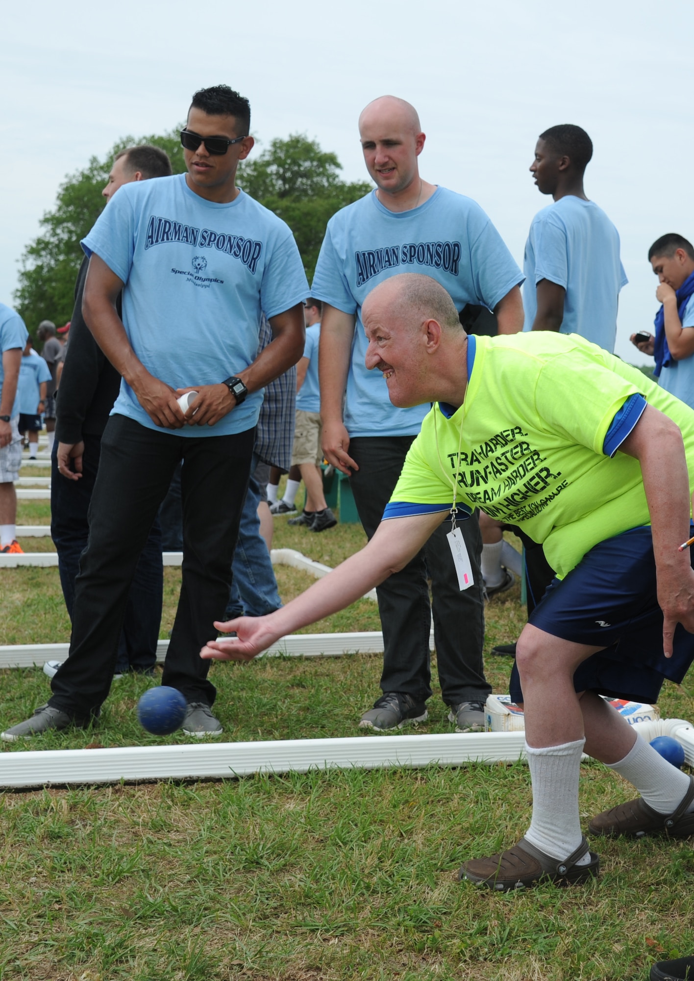 Marty Clark, athlete, tosses a bocce ball while being supported by his Airmen sponsors, Airman Roland Rios and Airman 1st Class Dane Sears, 335th Training Squadron, during the Special Olympics Mississippi Summer Games May 10, 2014, near  the triangle track, at Keesler Air Force Base, Miss.  More than 900 athletes and 3,000 volunteers worked together to hold competitions throughout the day.  This is the 28th year Keesler has hosted the state Special Olympics.  (U.S. Air Force photo by Kemberly Groue)