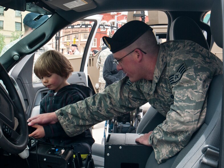Staff Sgt. Patrick Taylor, 90th Security Forces Squadron, shows Wyatt Deball, son of Cheyenne Police Department Sgt. Adam Deball, how to operate the radio in a law enforcement vehicle, which is used by defenders in the 90th SFS, May 10, 2014 in the Cheyenne, Wyo., Depot Square. 90th Security Forces Group personnel set up static displays in the Square for National Police Week. (U.S. Air Force photo by Airman 1st Class Jason Wiese)