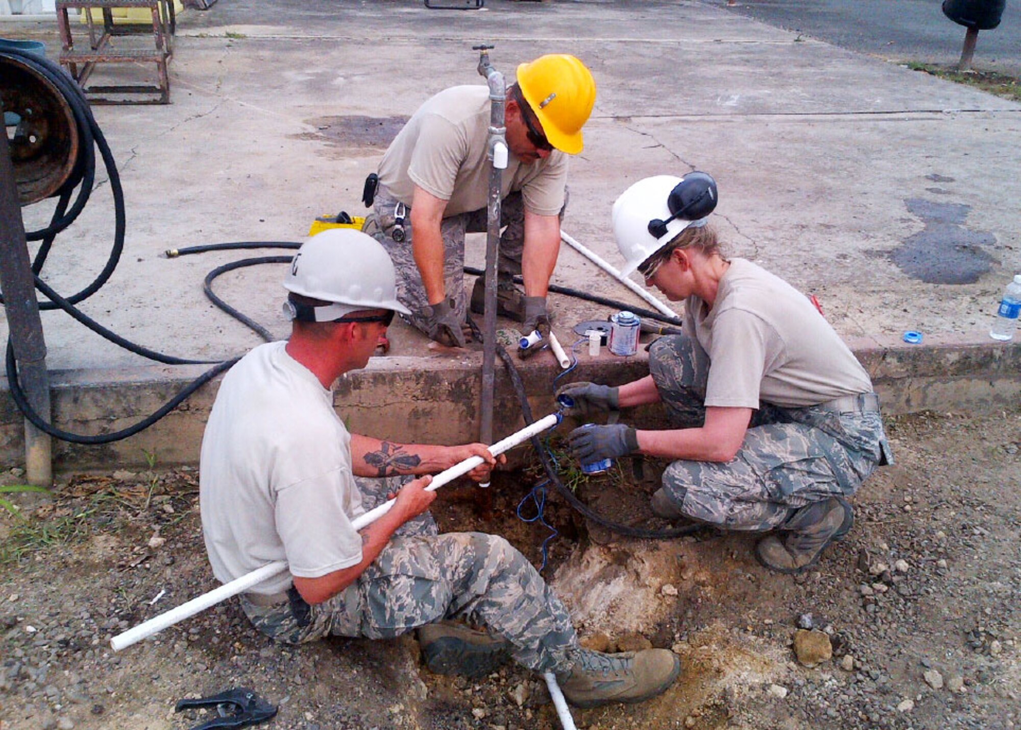 Col. Anne Gunter, 944th Mission Support Group Commander, assists Tech. Sgt. Brian Green and Staff Sgt. John Hampsey, 944th Civil Engineer Squadron water and fuels systems maintenance journeymen, as they route an adjacent water supply to the new hazardous material storage facility at Bellows Air Station, Hawaii. (U.S. Air Force photo/Tech. Sgt. Louis Vega Jr.)