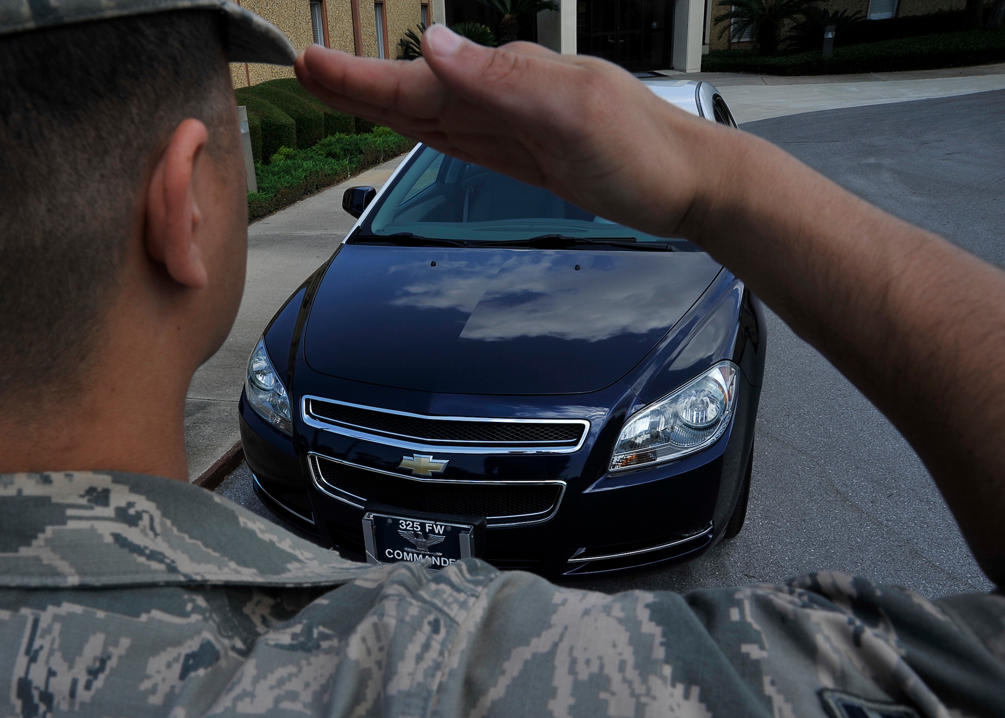 A Tyndall Airmen simulates saluting a staff car with proper officer identification May 13 at the Fighter Wing Headquarters. Airmen are expected to render the proper customs and courtesies whether officers are walking or driving passed. (U.S. Air Force photo by Solomon Cook)