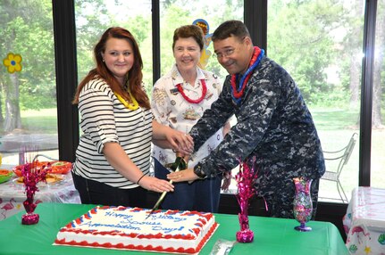 Jan Hill, representing the Navy Wife's Club of America (center), Navy spouse Jecie Chipman, and Cmdr. David Tarwater, Naval Support Activity executive officer, cut a cake in honor of Military Spouse Appreciation Month during a Cake and Ice Cream Social May 9, 2014, at the Fleet & Family Support Center, on Joint Base Charleston – Weapons Station. (U.S. Navy photo/ Kris Patterson)
