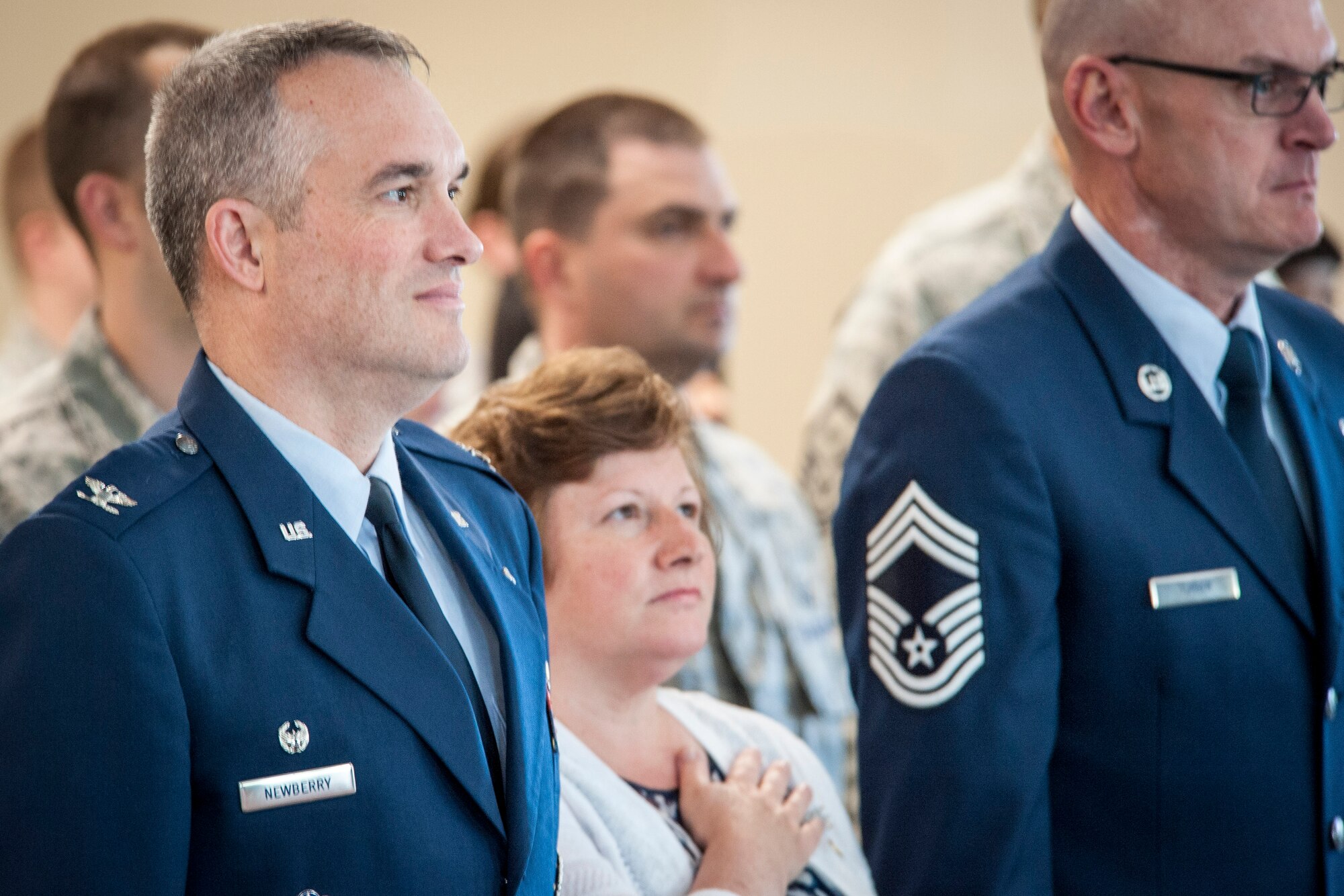 Col. Brian Newberry, his wife, Jill, and Chief Master Sgt. Lance Turner, along with other graduation attendees honor Old Glory during the singing of the Star Spangled Banner during the Fairchild Honor Guard graduation ceremony in the Red Morgan Event Center at Fairchild Air Force Base, Wash., May 9, 2014. Fairchild’s honor guard performs military honors for various events and ceremonies across the Inland Northwest every week as the installation’s front-line ambassadors. Each member from nearly every career field serves a four month rotation. Newberry is the 92nd Air Refueling Wing commander and Turner is the 92nd ARW acting command chief. (U.S. Air Force photo by Staff Sgt. Benjamin W. Stratton/Released)