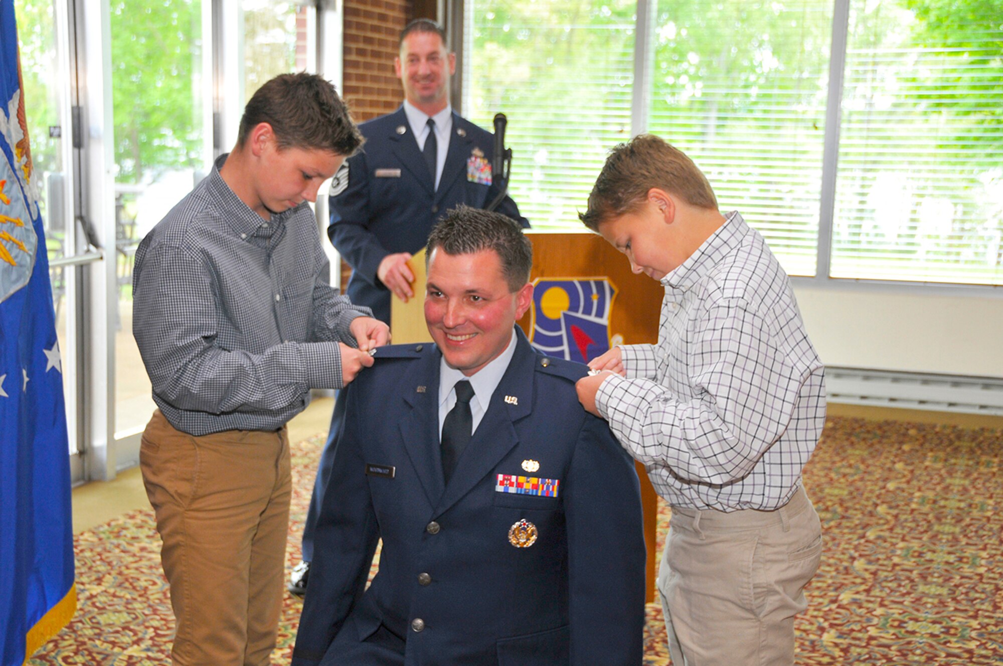 During a recent promotion ceremony at AEDC, Aaron Woodward (center), the director of the Arnold Air Force Base Staff Judge Advocate Office, was promoted to the rank of lieutenant colonel. Woodward's sons Logan Woodward (left) and Caleb Woodward (right) pin on their father's new rank as Master Sgt. George Allen looks on. Woodward's ceremony was also attended by his wife Laurie Woodward, and his parents Robert and Vicki Woodward. (photo provided by Jacqueline Cowan)
